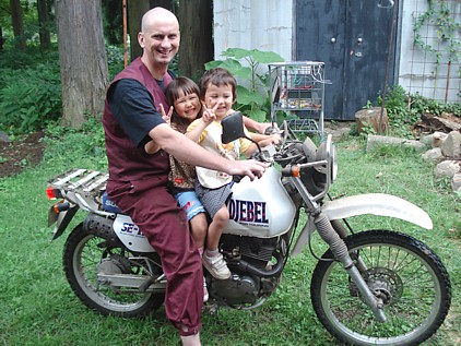 Abbot Muho with kids on motorbike.